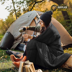 PrepPro Australia wearable black quilted camping blanket draped over a woman sitting by a tent outdoors