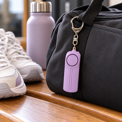 Purple personal alarm clipped to a gym bag